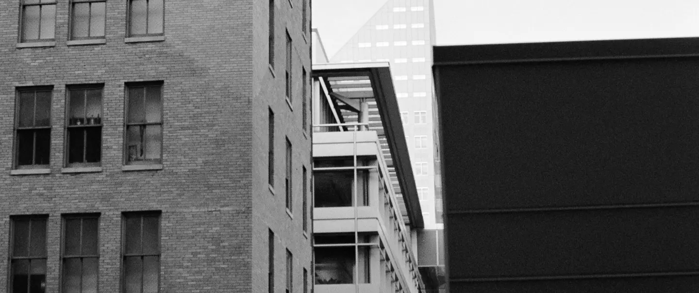 Black and white photo of plane flying over downtown skyline